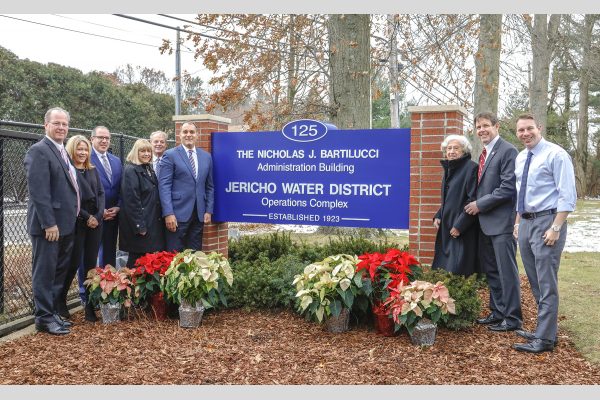 Group photo at sign dedication, Nicholas J. Bartilucci Administration Building, Jericho Water District. Left to right Jericho Water District Commissioner James Asmus; Oyster Bay Town Council member Vicki Walsh; Oyster Bay Town Clerk Richard LaMarca; Jericho Water District Commissioner Patricia Beckerle; Jericho Water District Board Chairman Commissioner Thomas Abbate; Town of Oyster Bay Supervisor Joseph Saladino; Mrs. Joan Bartilucci; Jericho Water District Superintendent Peter Logan; Nassau County Legislator Josh LaFazan (18th Legislative District).